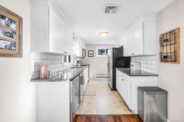 a kitchen with stainless steel appliances granite countertop a sink stove refrigerator and cabinets
