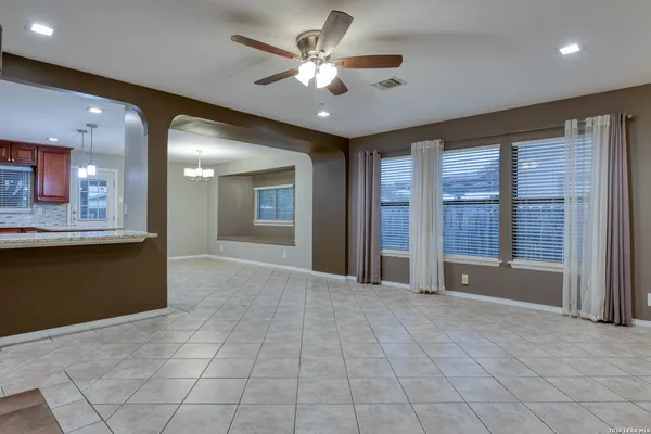 a view of an empty room with a chandelier fan and windows