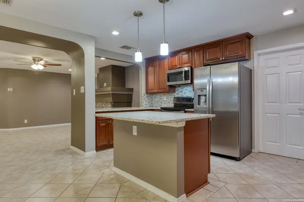 a large kitchen with stainless steel appliances granite countertop a stove a sink a refrigerator and a microwave
