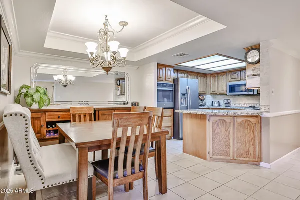 a kitchen with stainless steel appliances kitchen island granite countertop a table chairs and a chandelier