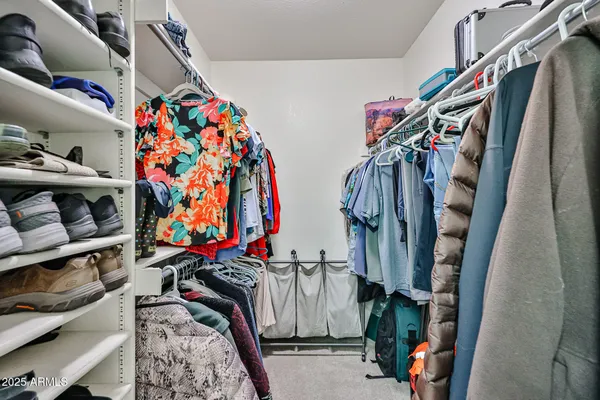 a view of walk in closet with clothes and shoes