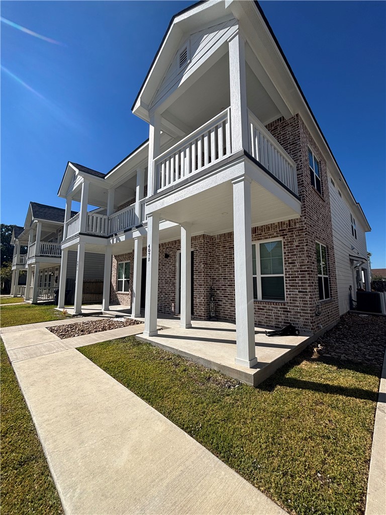 407 Ash Street College Station, TX 77840 - Photo 2 of 14 Rear view of house with a balcony, brick siding, a lawn, and a patio