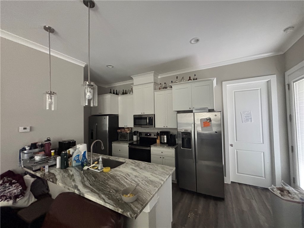 407 Ash Street College Station, TX 77840 - Photo 3 of 14 Kitchen with appliances with stainless steel finishes, decorative light fixtures, crown molding, white cabinets, and a peninsula