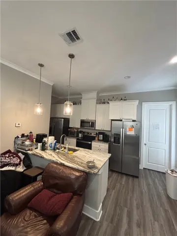 a kitchen with stainless steel appliances kitchen island granite countertop a refrigerator a sink dishwasher a stove and a dining table with wooden floor