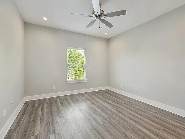 an empty room with a window and a ceiling fan