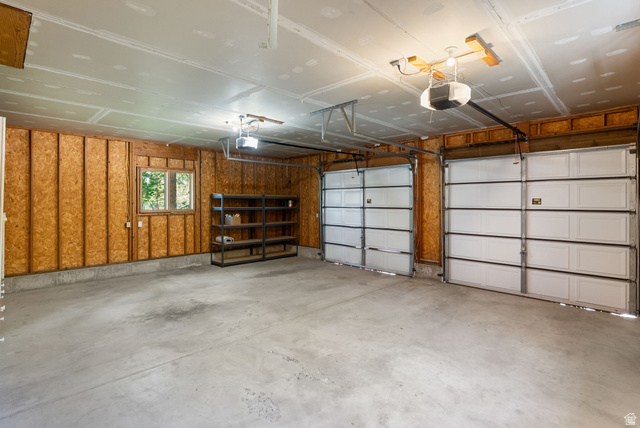 435 Canyon Road Millville, UT 84326 - Photo 24 of 113 Spacious two-car garage featuring a concrete floor, exposed wood-paneled walls, and a window for natural light