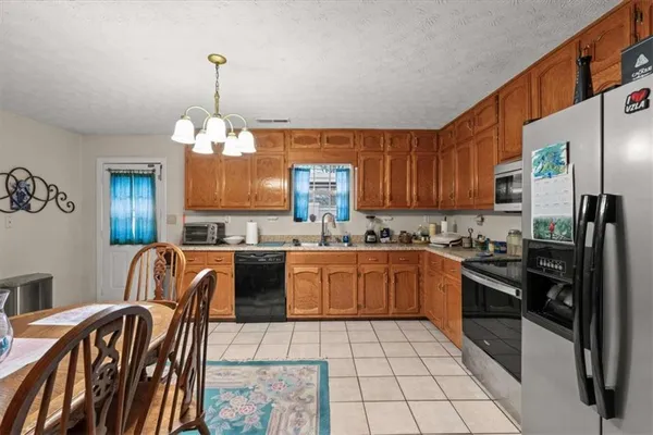 a kitchen with granite countertop stainless steel appliances a stove top oven a sink a dining table and chairs