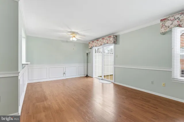 an empty room with wooden floor chandelier fan and windows