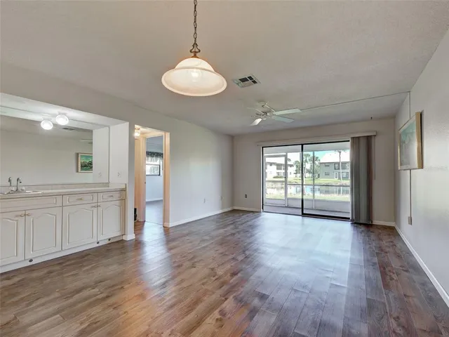 a view of an empty room with wooden floor and a ceiling fan