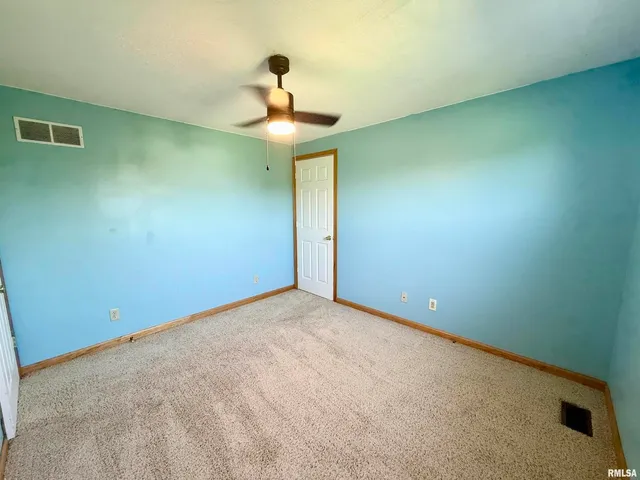 a view of an empty room with a chandelier fan