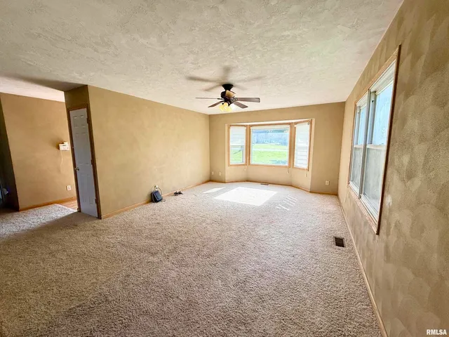 a big room with windows and a chandelier fan