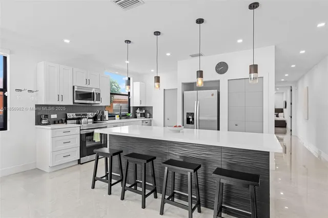 a kitchen with stainless steel appliances kitchen island a refrigerator and a stove top oven
