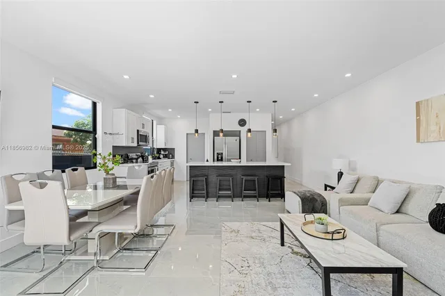 a living room with furniture a kitchen view and a flat screen tv