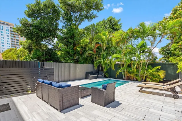 a view of a backyard with couches plants and large tree