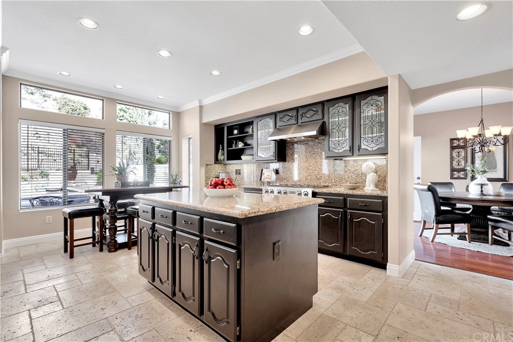 1600 Canyon Crest Circle Corona, CA 92882 - Photo 21 of 74 a kitchen with stainless steel appliances granite countertop a stove top oven a sink dishwasher a dining table and chairs with wooden floor