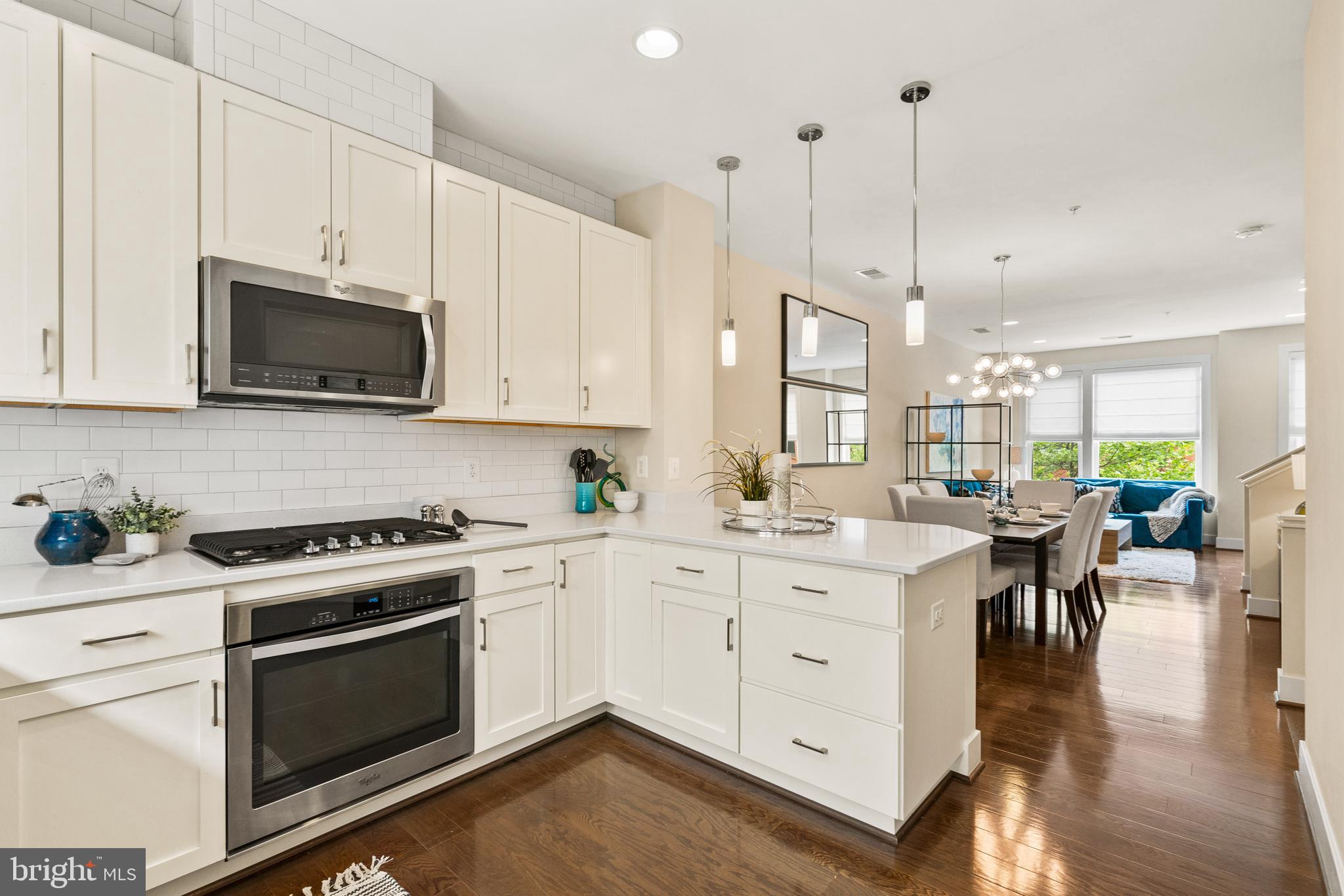 a kitchen with a white stove top oven and white cabinets with wooden floor