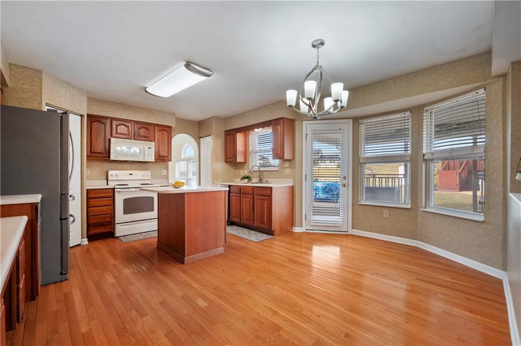 208 Commodore Drive McDonald, PA 15057 - Photo 7 of 36 a open kitchen with stainless steel appliances granite countertop a stove top oven a refrigerator a sink dishwasher with a dining table and chairs with wooden floor