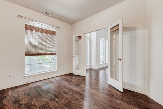 an empty room with wooden floor and windows