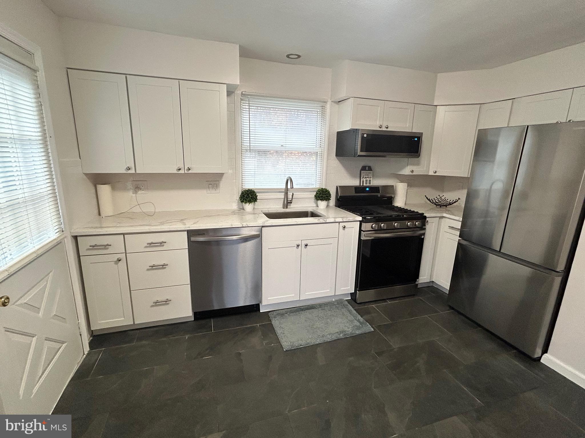 69 Wickom Avenue Hamilton, NJ 08690 - Photo 11 of 14 a kitchen with white cabinets stainless steel appliances and a sink