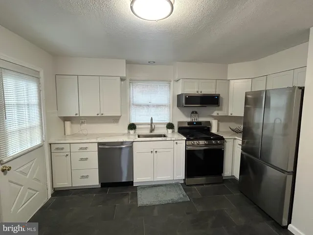 a kitchen with white cabinets and stainless steel appliances