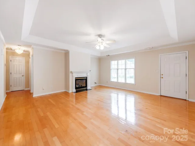 a view of an empty room with window and wooden floor