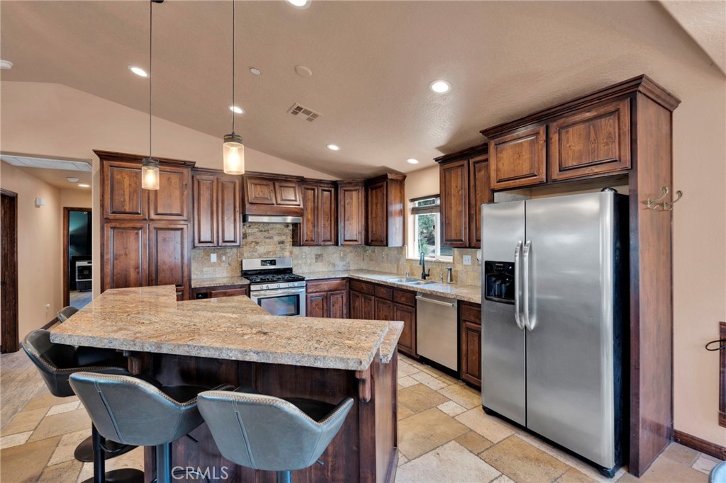 7635 Desert Front Road Wrightwood, CA 92397 - Photo 11 of 60 a kitchen with stainless steel appliances granite countertop a refrigerator a stove a sink a dining table and chairs
