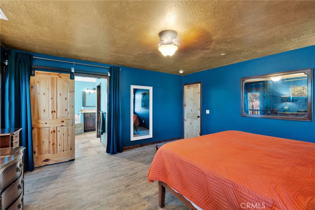 7635 Desert Front Road Wrightwood, CA 92397 - Photo 18 of 60 a bedroom with a large bed chandelier and a flat screen tv