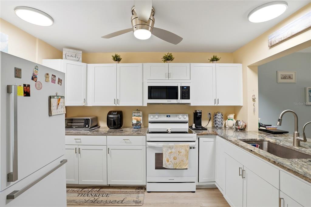 12300 Vonn Road, Unit 7104 Largo, FL 33774 - Photo 7 of 41 a kitchen with stainless steel appliances a stove a sink a refrigerator a microwave and cabinets