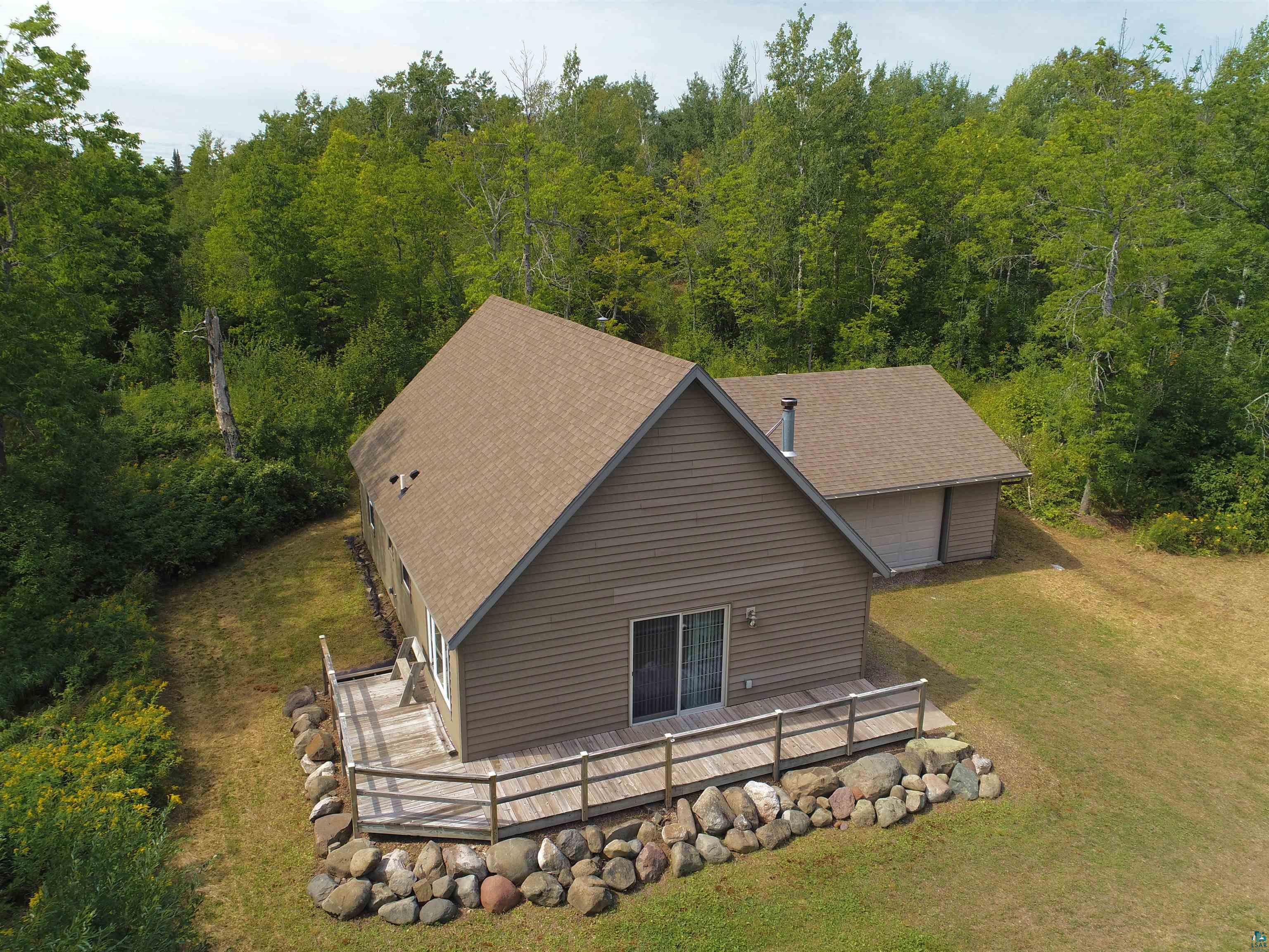 Exterior siding with attached deck, sliding glass door, and surrounding mature trees
