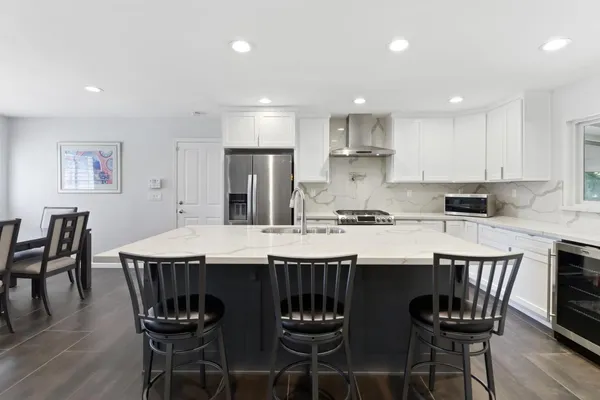 a kitchen with stainless steel appliances granite countertop a dining table chairs and sink