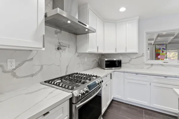 a kitchen with stainless steel appliances a stove a sink and white cabinets