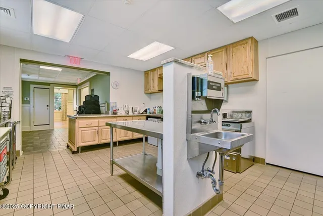 a room with stainless steel appliances kitchen island granite countertop a refrigerator and a sink