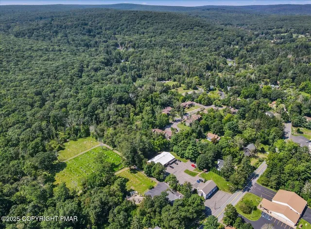 an aerial view of residential house with outdoor space and trees all around