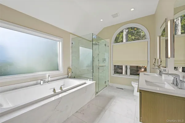 a spacious bathroom with a tub a double vanity sink a mirror and a shower