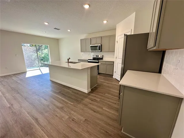 a kitchen with stainless steel appliances a refrigerator sink and wooden floor