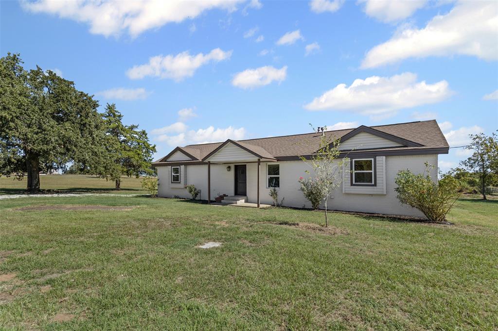 a house that is sitting in the grass with large trees
