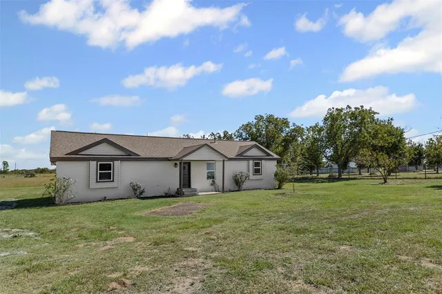 a view of a big house with a big yard and large trees