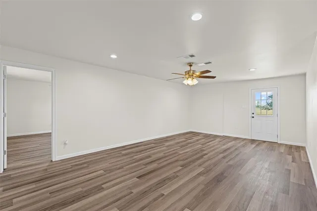 a view of empty room with wooden floor and fan