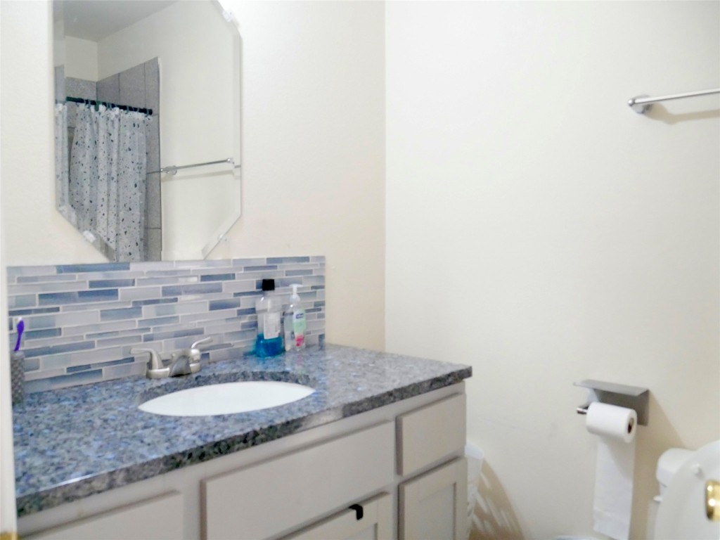 1013 Price Street Taylor, TX 76574 - Photo 12 of 12 a bathroom with a granite countertop sink and a mirror