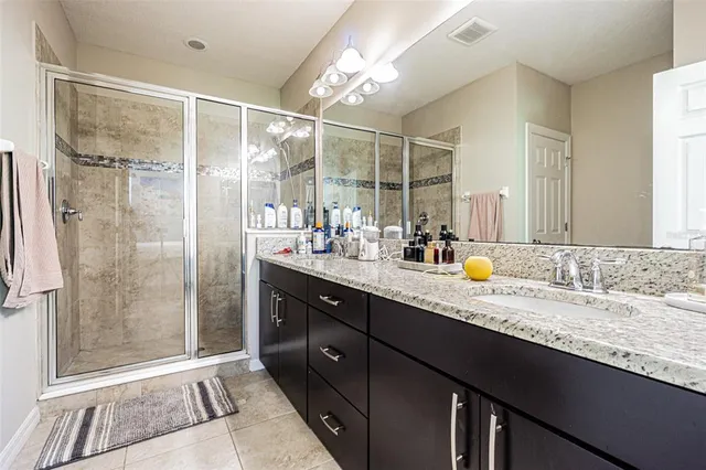 a bathroom with a granite countertop sink a mirror and a shower