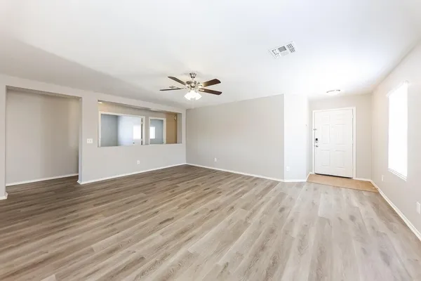 an empty room with wooden floor and windows
