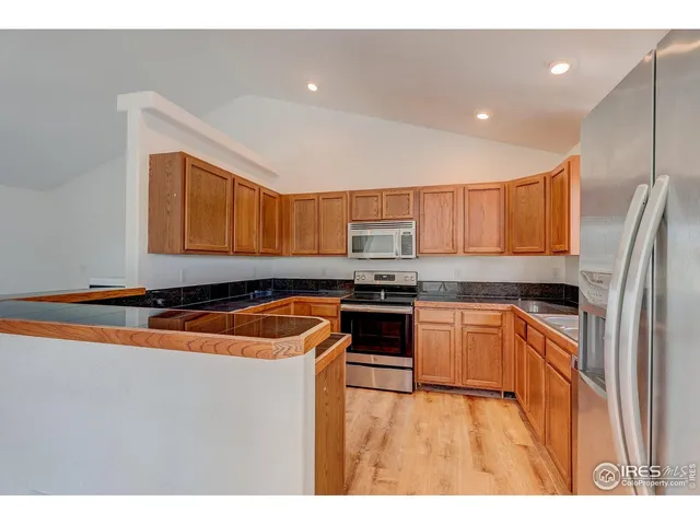 a kitchen with stainless steel appliances granite countertop a refrigerator a stove and a sink