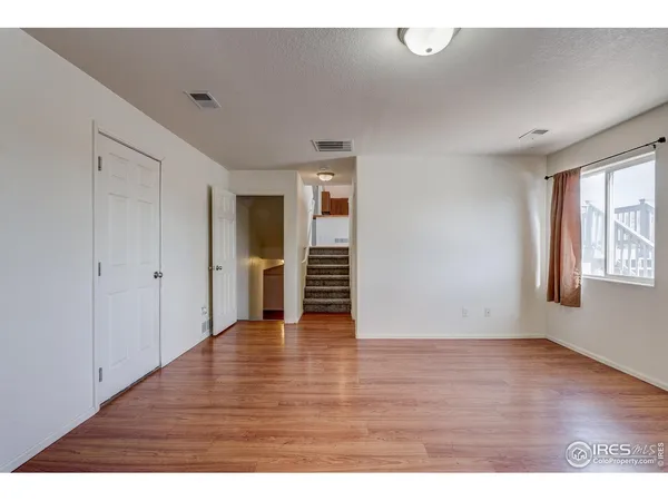 a view of an empty room with wooden floor and windows