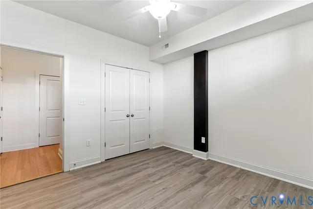 an empty room with wooden floor and windows