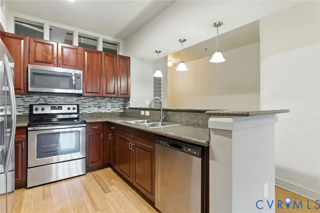 a kitchen with kitchen island granite countertop a sink cabinets and stainless steel appliances
