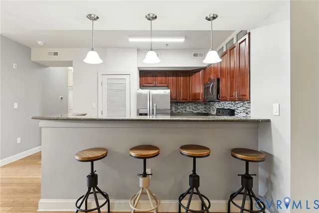 a kitchen with stainless steel appliances a table chairs refrigerator and microwave