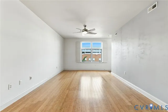 an empty room with windows and ceiling fan