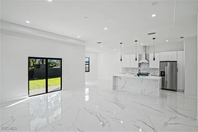 a large white kitchen with stainless steel appliances granite countertop a stove a sink a refrigerator and white cabinets with wooden floor