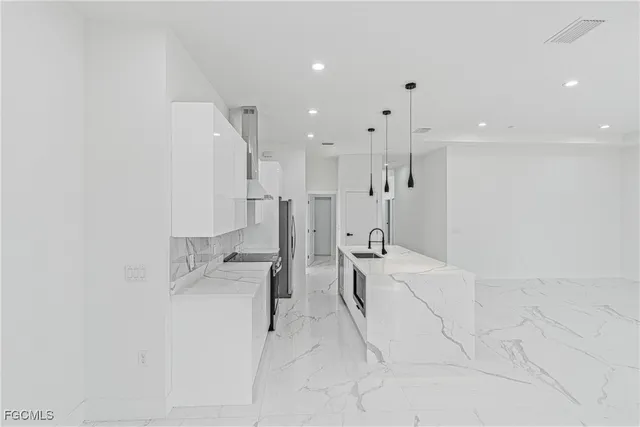 a view of a kitchen with a sink and dishwasher a refrigerator with white cabinets