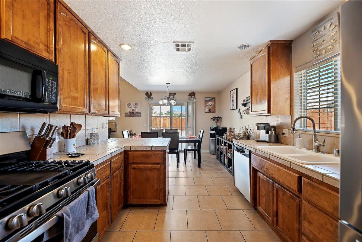 7562 Inca Trail Yucca Valley, CA 92284 - Photo 15 of 30 a kitchen with stainless steel appliances granite countertop a stove top oven a sink dishwasher a dining table and chairs